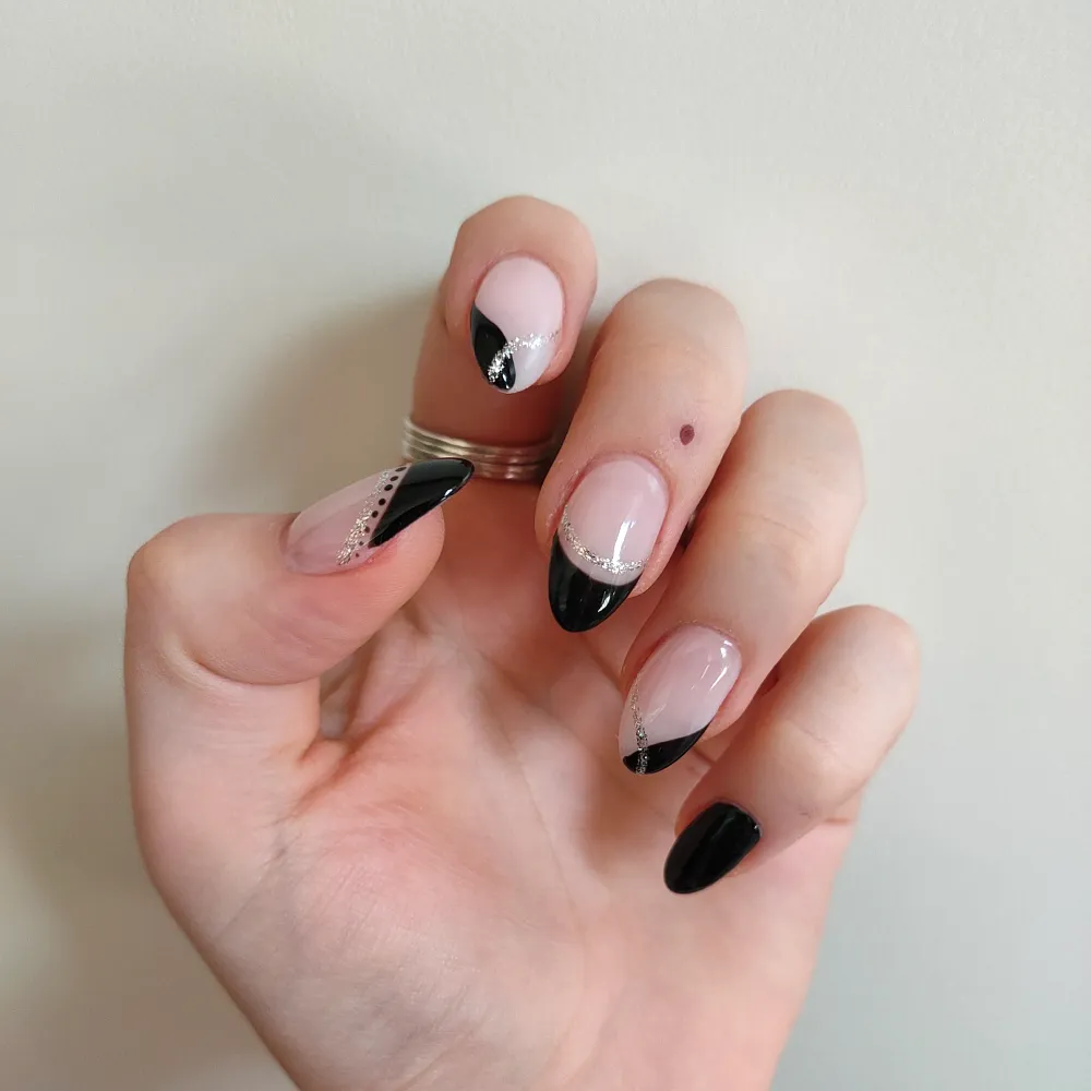 Almond-shaped nails with black French tips and fine glitter detail